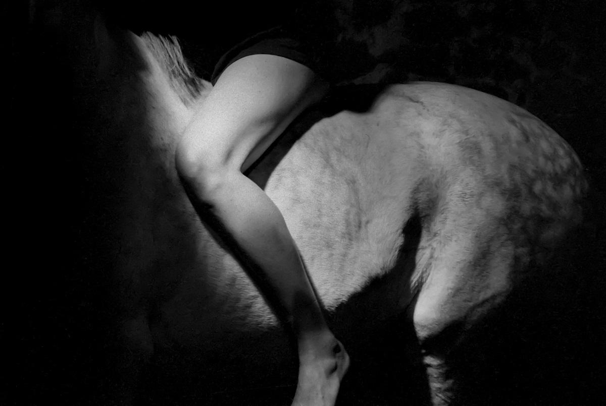 Photographie en noir et balnc d'une femme sur un cheval