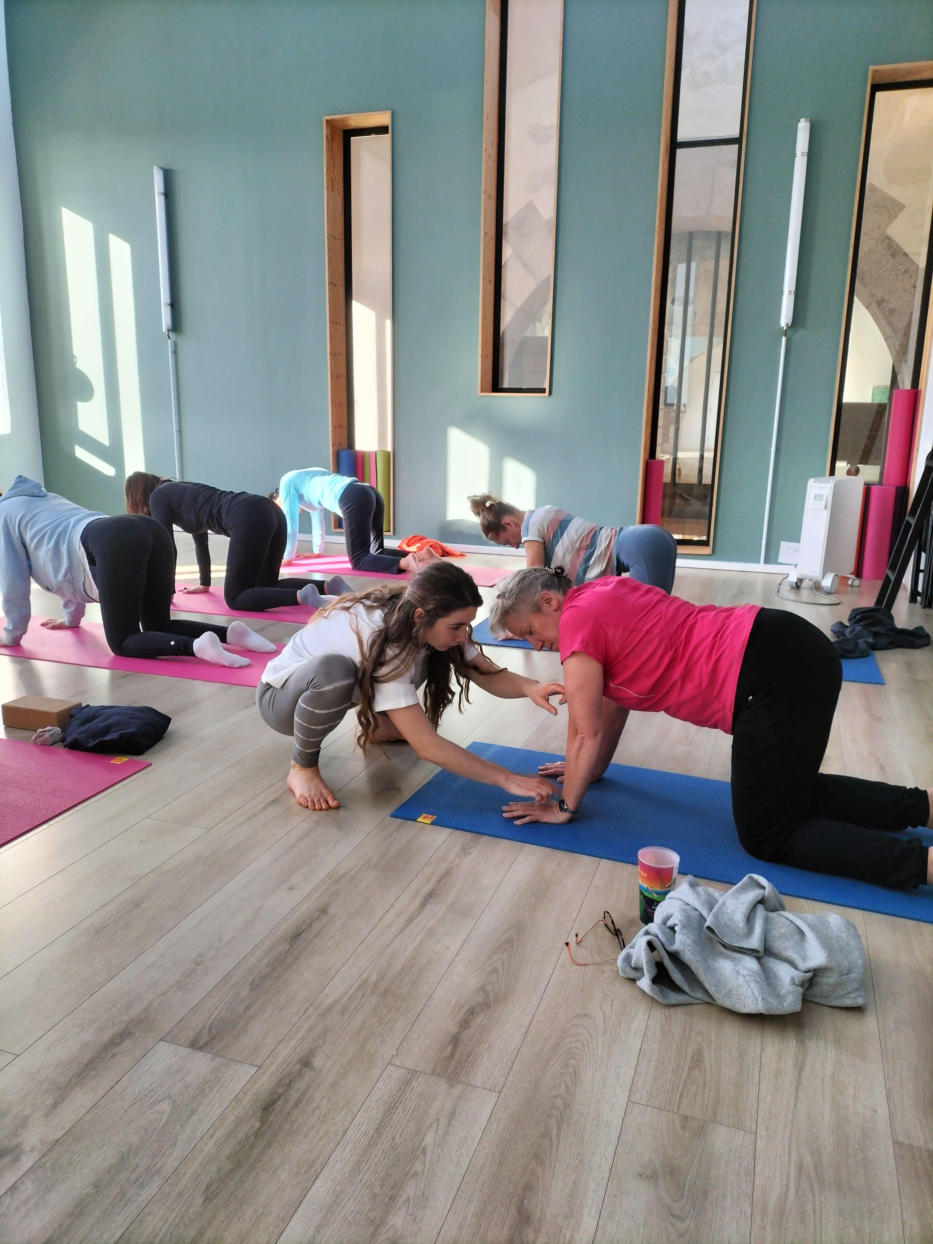 Une professeure de Yoga aidant une pratiquante