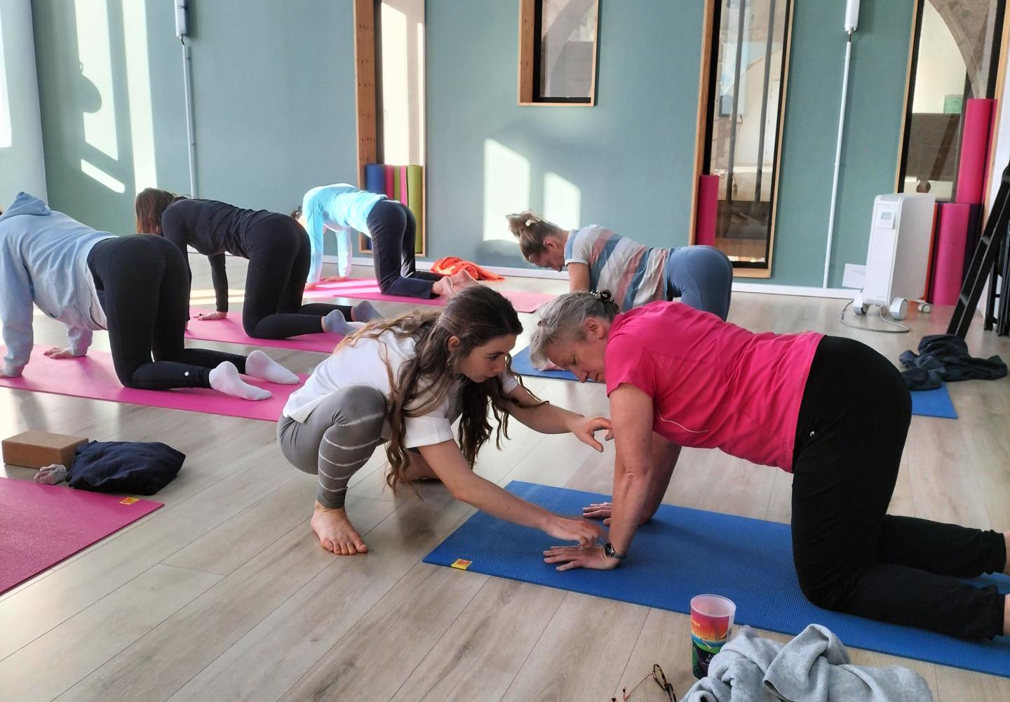 Une professeure de Yoga aidant une pratiquante
